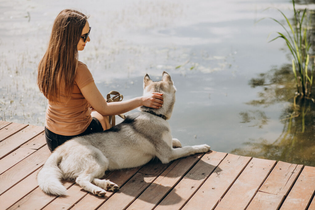 Chica junto a un estanque con su perro libre de parásitos